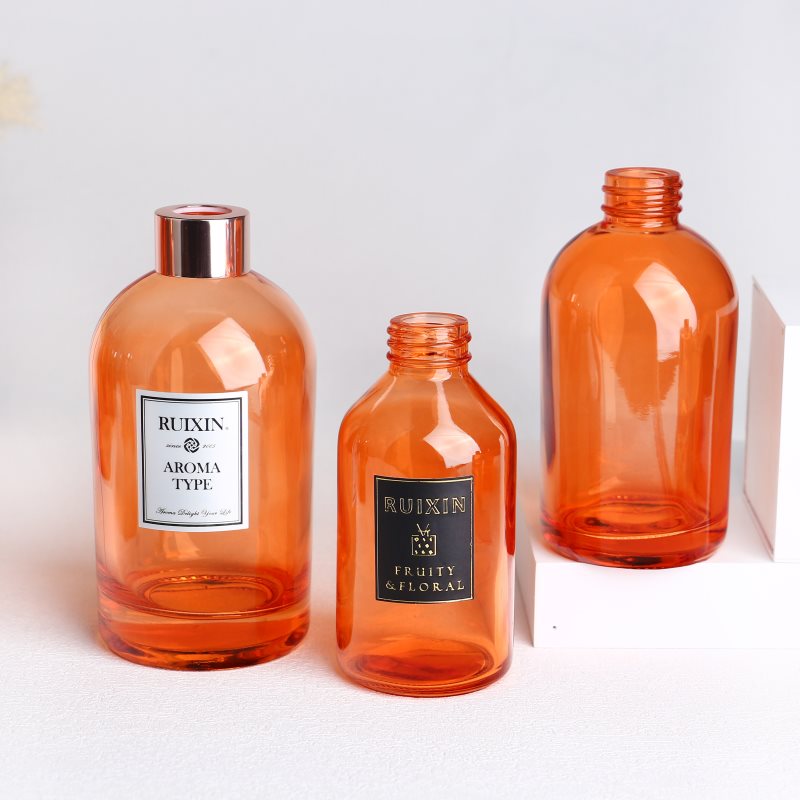 Botellas difusoras redondas de color naranja con etiquetas, tapas y cuello de rosca