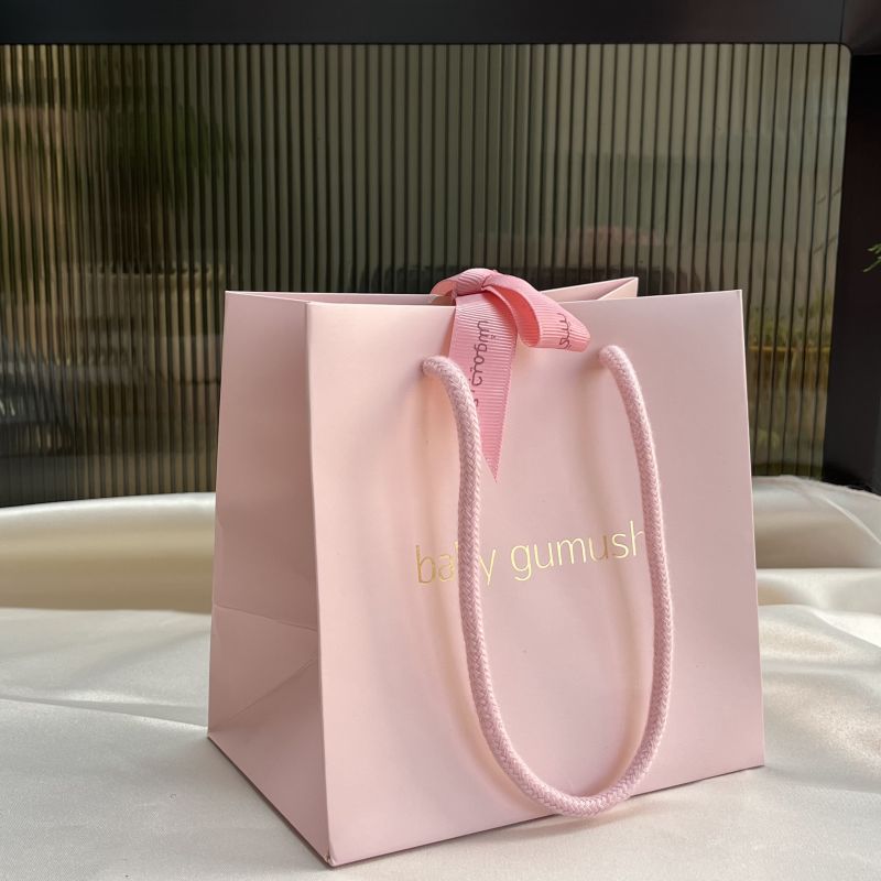 Pink gift bag for jewelry packaging with ribbon on the middle
