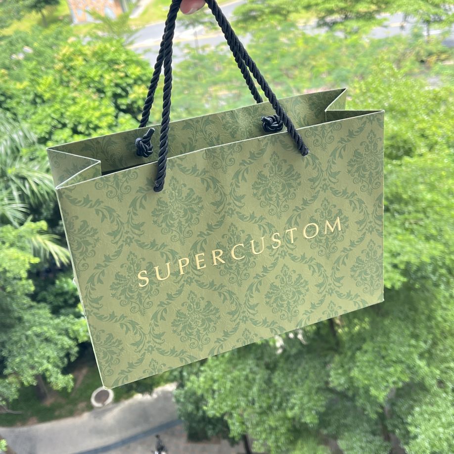 Saco de papel de luxo em papel extravagante personalizado de cor verde acabada com textura em relevo na superfície com logotipo dourado