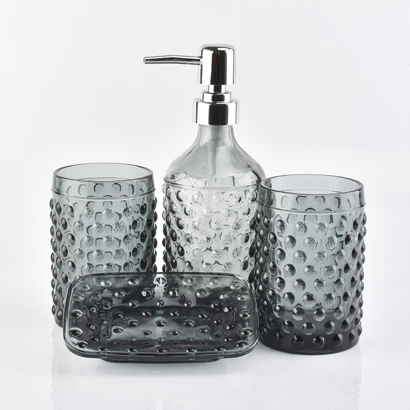 bottiglie di vetro grigio fumoso, bicchieri, portasapone per il bagno in albergo