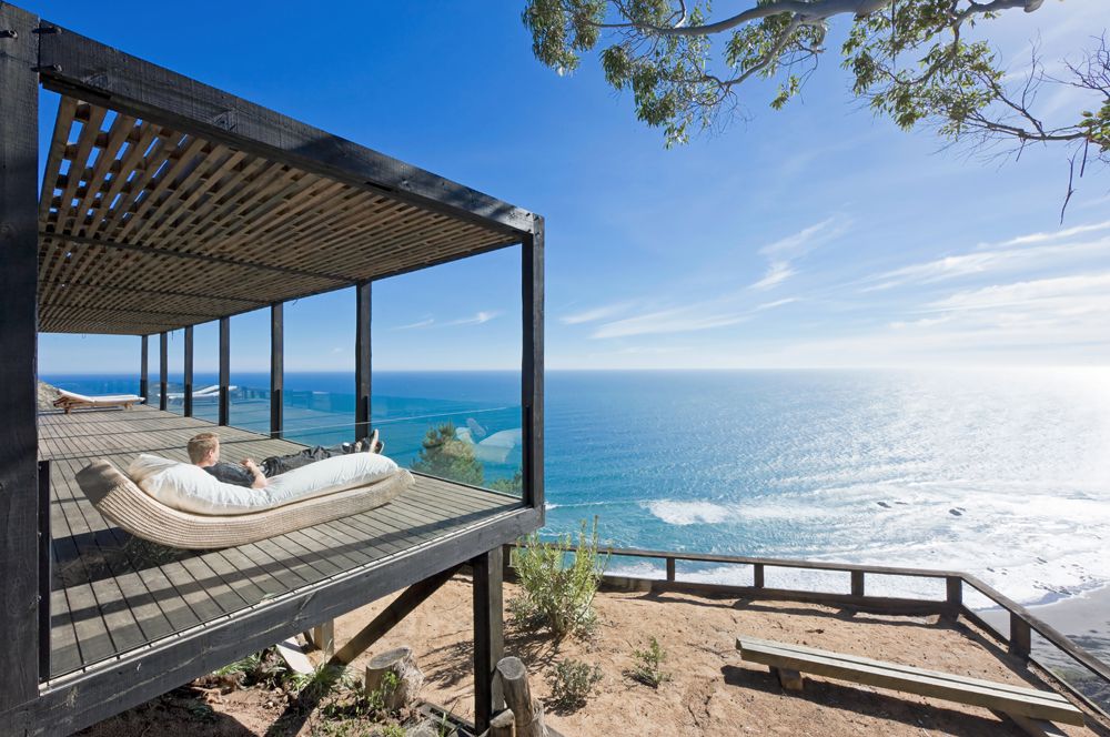 Uma casa pré-fabricada de vidro ligada ao céu azul e ao mar